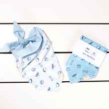 Two dog bandanas on a white table top. Left has a white bandana with dark blue illustrations tied with a knot. Right has a light blue folded bandana with dark blue illustrations.